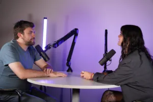 Podcast à deux avec micros sur bras articulés, décor béton éclairé en violet