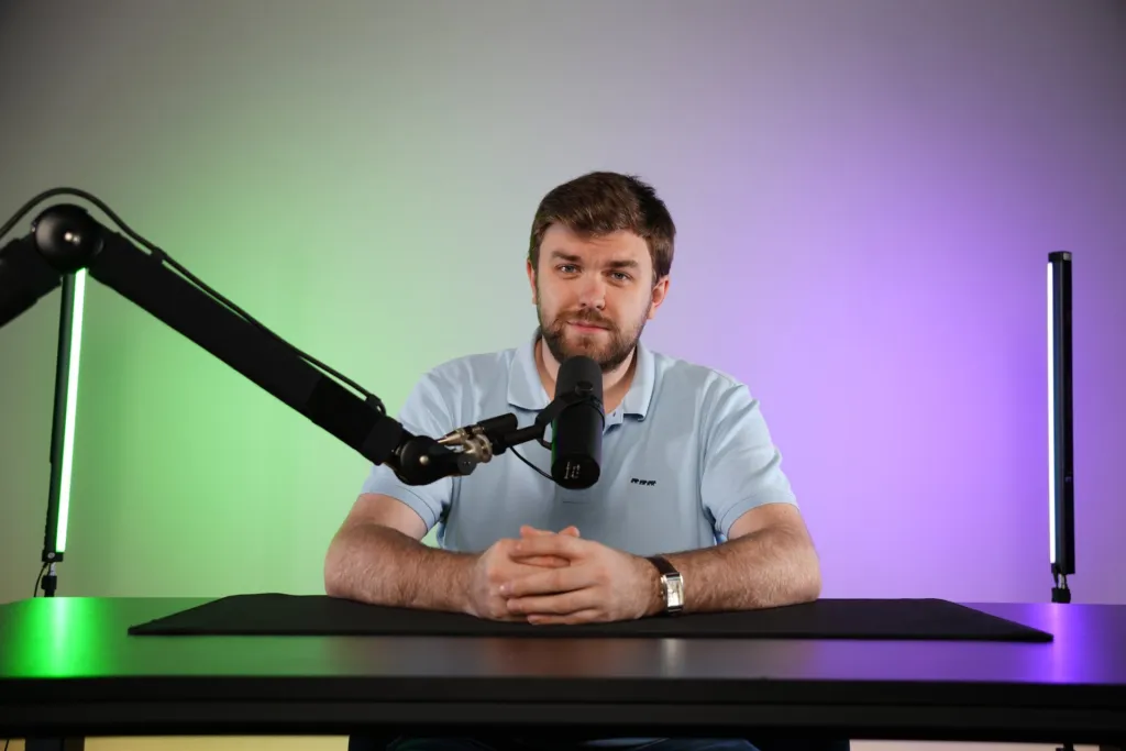 Podcast en solo au bureau avec micro sur bras, décor béton éclairé en vert et violet