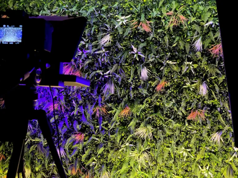 Caméra et prompteur face au mur végétal du studio Le 21